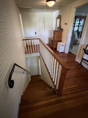 Eine Holztreppe mit weißen Geländern, die zu einer Empore führt.