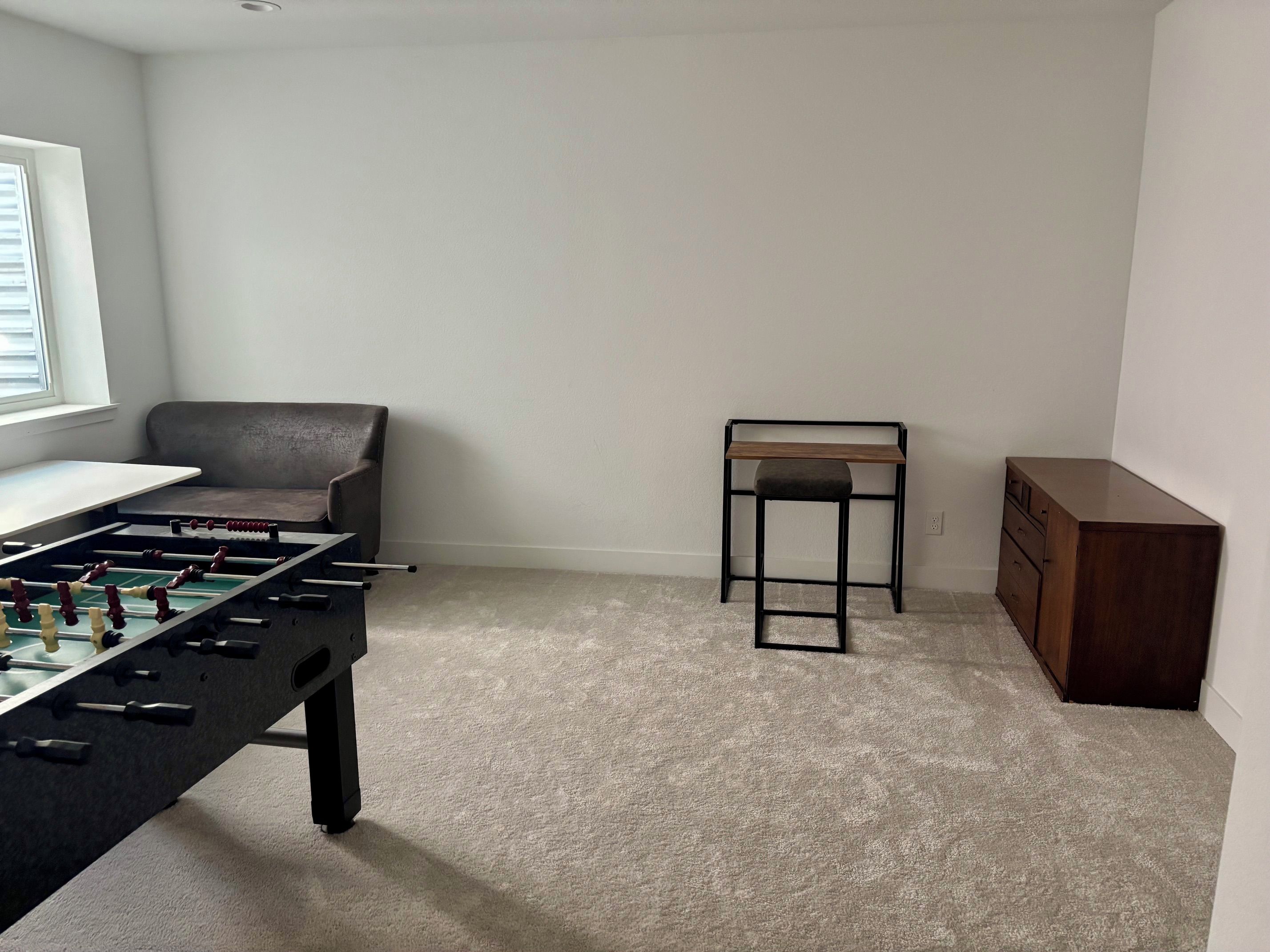 Ein Zimmer mit einem Kicker, einem Sofa, einem kleinen Tisch und einem Schrank.