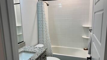 Une salle de bain avec douche, toilettes et lavabo.