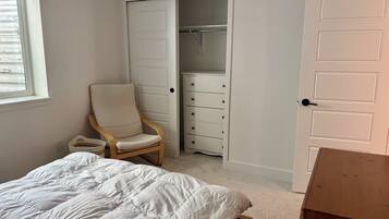A bedroom with a bed, a chair, a wardrobe, and a door.