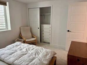 A bedroom with a bed, a chair, a wardrobe, and a door. - Full basement queen&bath. US36 & trail access (Superior)