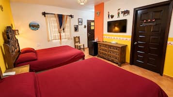 A hotel room with two beds, a wooden dresser, a TV, and a door with a decorative handle.