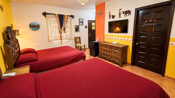 A hotel room with two beds, a wooden dresser, a TV, and a door with a decorative handle.