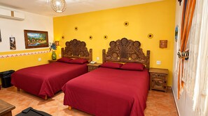 A room with two beds, a wooden headboard, a wall clock, and a painting.