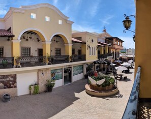 A courtyard with a building featuring a balcony, a fountain, and outdoor seating.