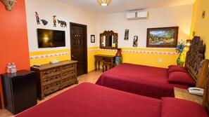 A hotel room with two beds, a TV, a dresser, and a desk with a chair.