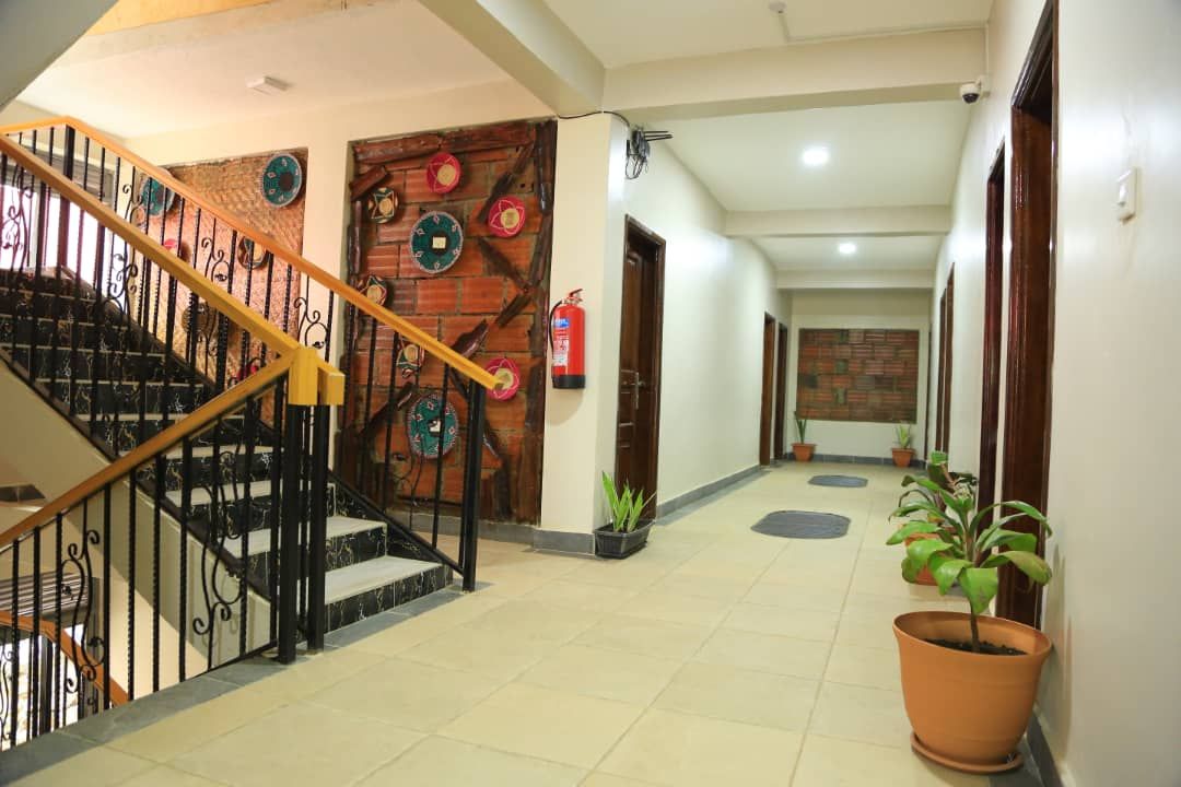 A hotel hallway with a staircase, a fire extinguisher, and potted plants.
