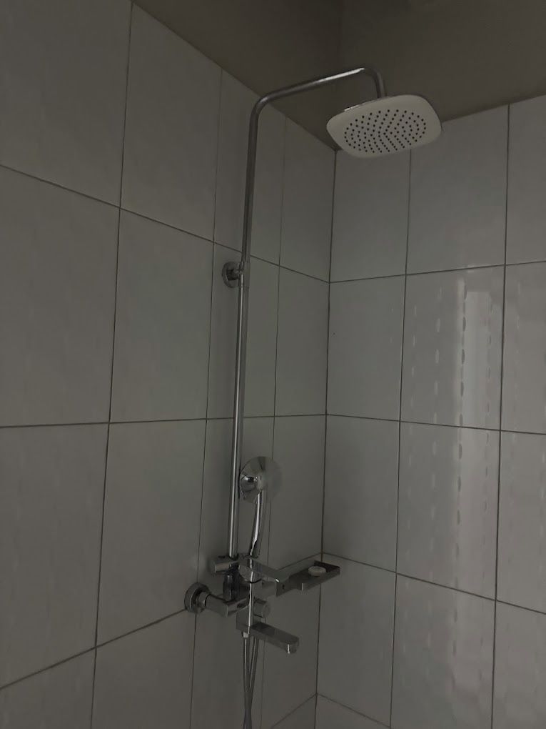 A shower with a handheld showerhead and a wall-mounted rain showerhead in a tiled bathroom.