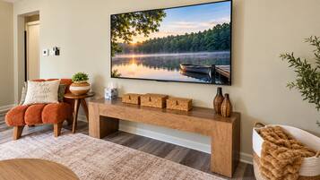 A living room with a large painting of a lake, a wooden bench, and a small table with decorative items.