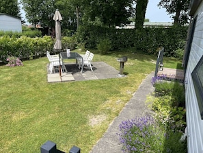 A backyard with a patio table and chairs, a bird bath, and a garden with various plants.