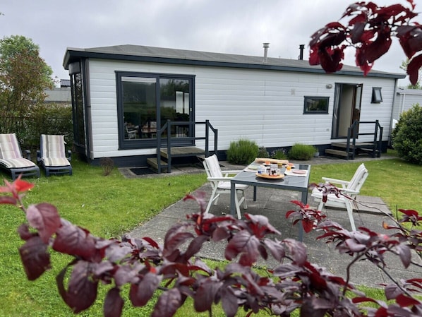 A single-story house with a patio area, outdoor seating, and a small garden.