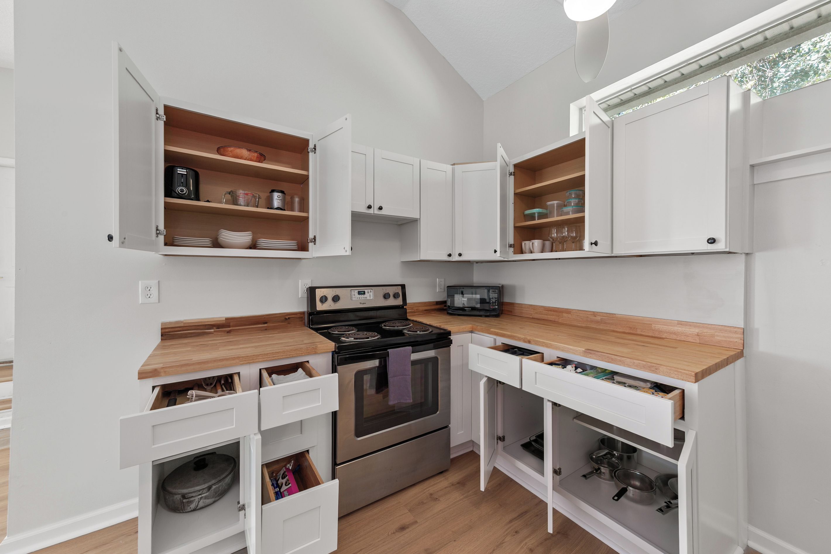 A compact kitchen with white cabinetry, a built-in oven, and a microwave.