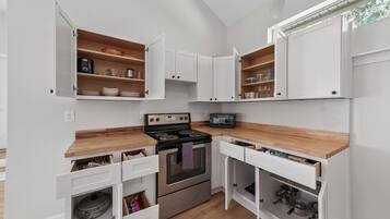 A compact kitchen with white cabinetry, a built-in oven, and a microwave.