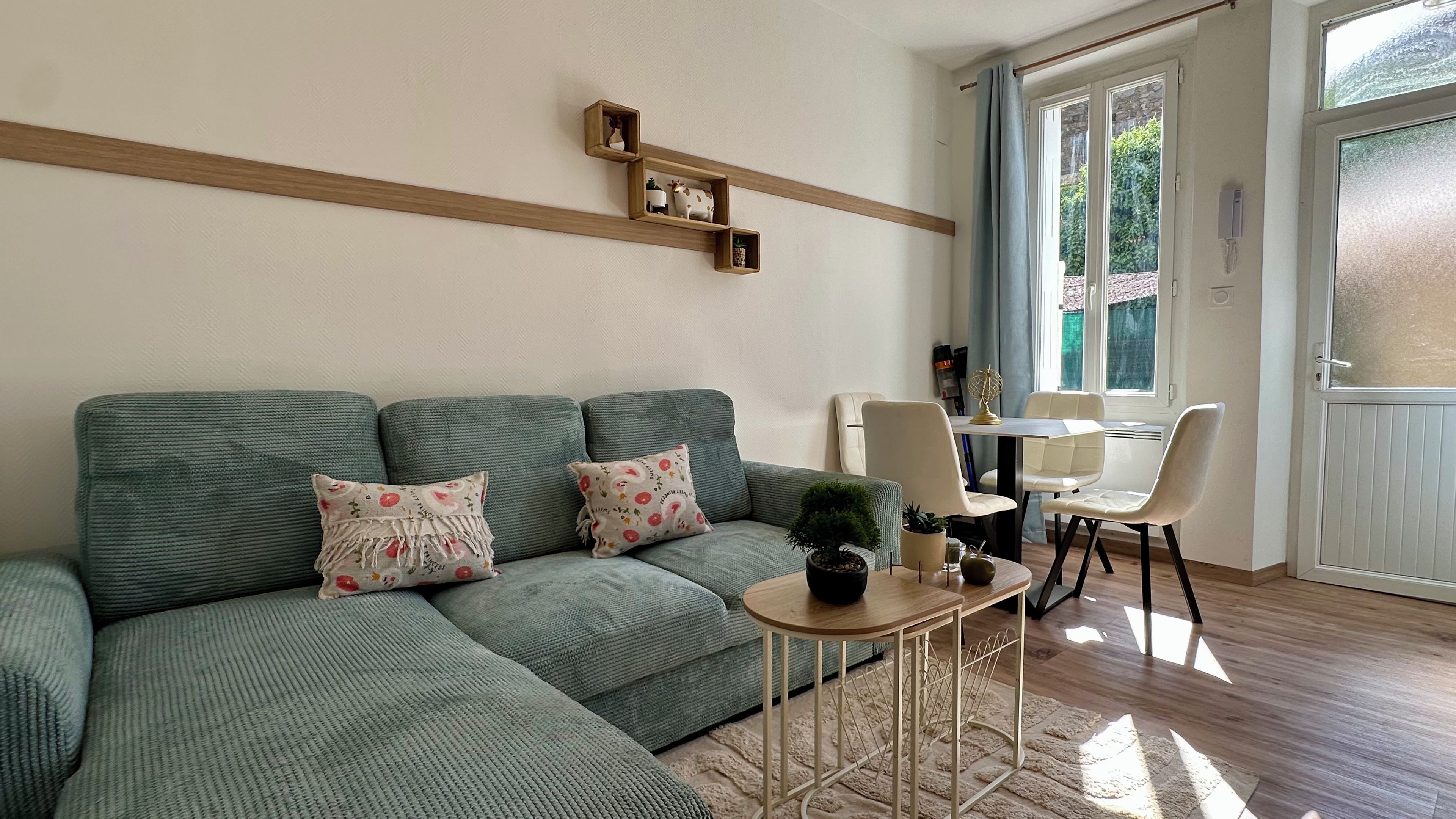Un salon avec un canapé vert, une petite table ronde et une plante en pot.