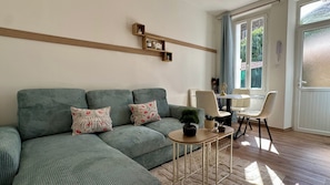 Un salon avec un canapé vert, une petite table ronde et une plante en pot.