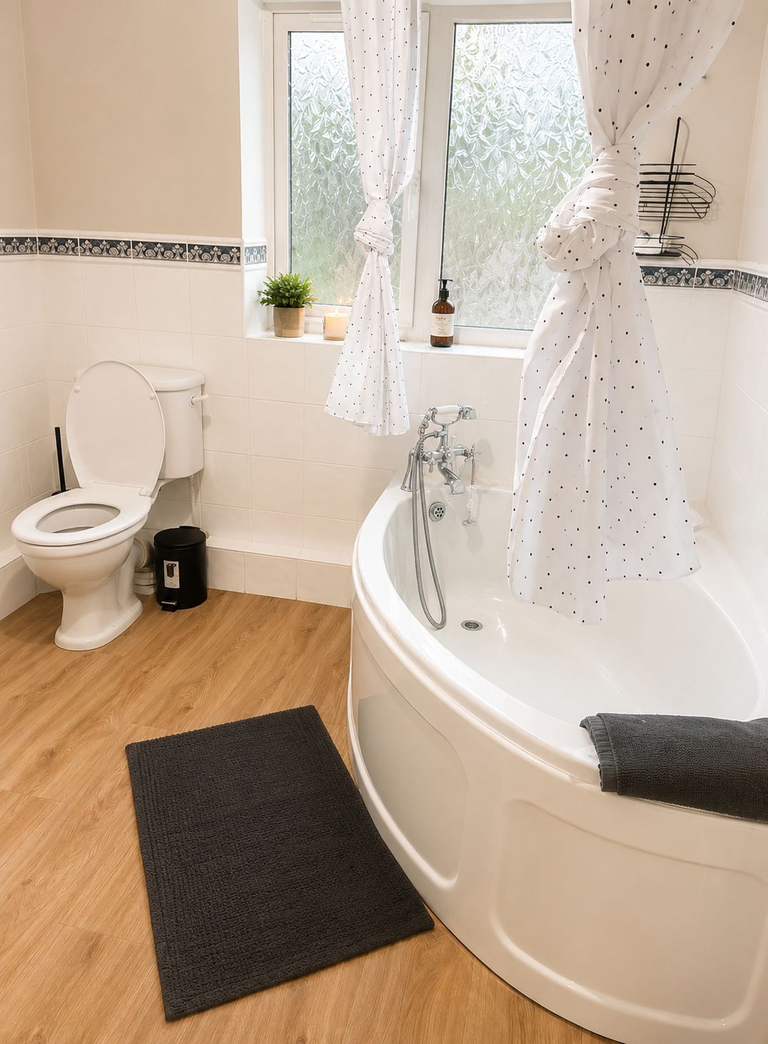 A modern bathroom with a toilet, a bathtub, and a window with curtains.