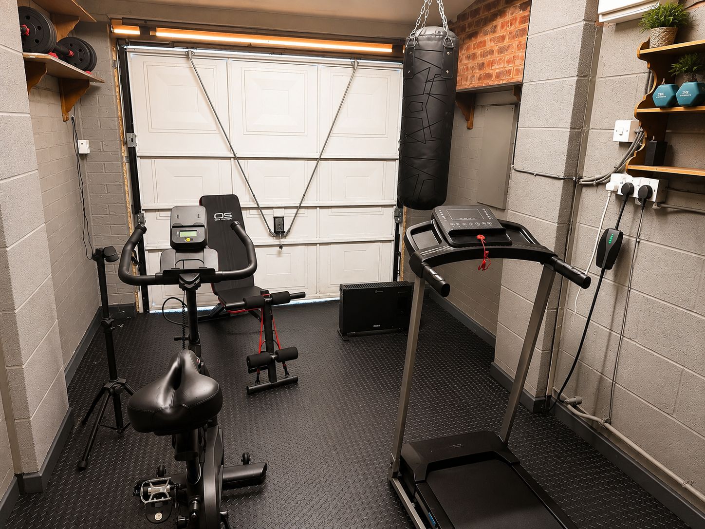 Ein Heimfitnessraum mit Ergometer, Laufband und einer Hantelbank.