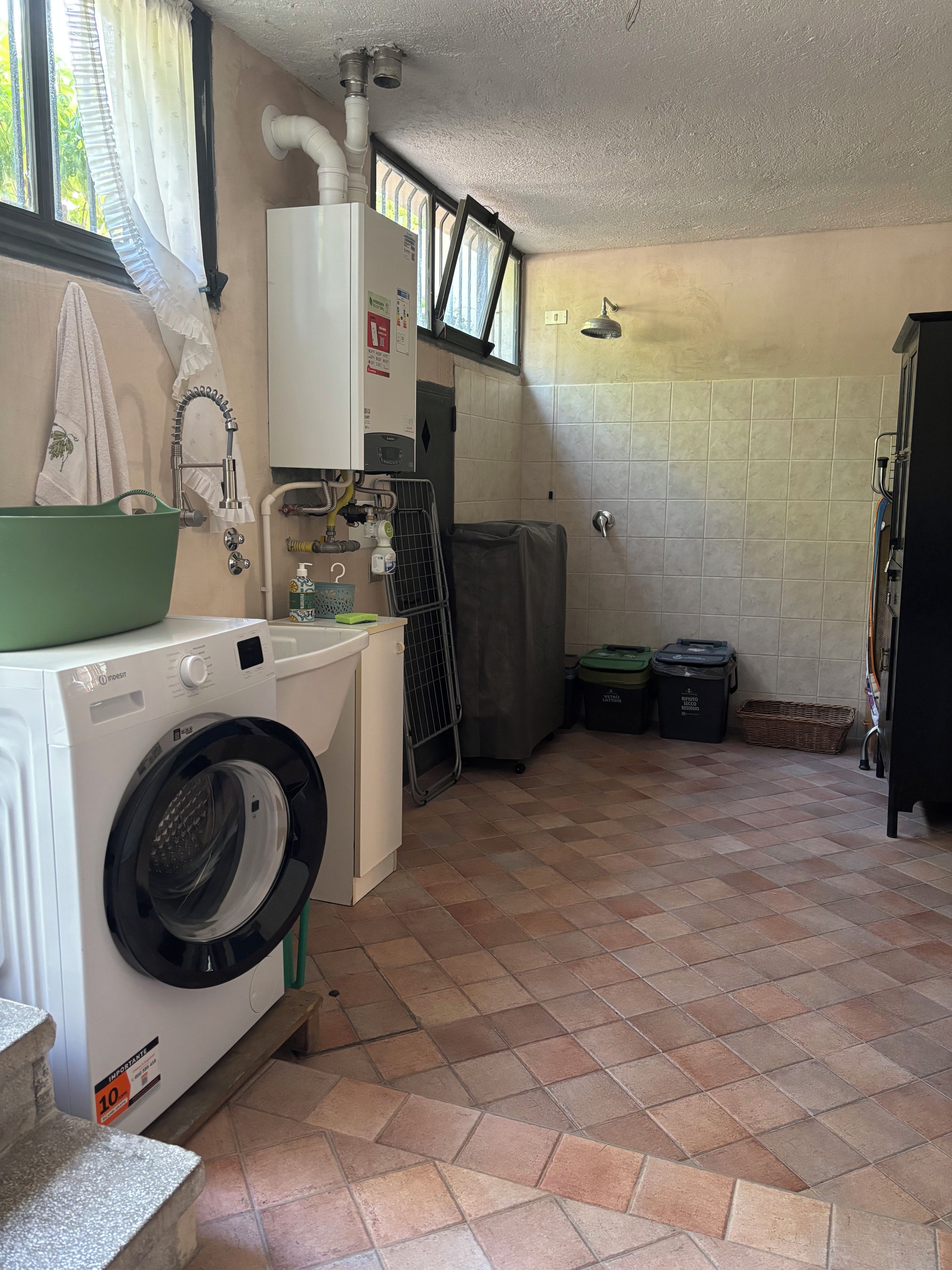 A laundry area with a washing machine, a drying rack, and a covered shower.