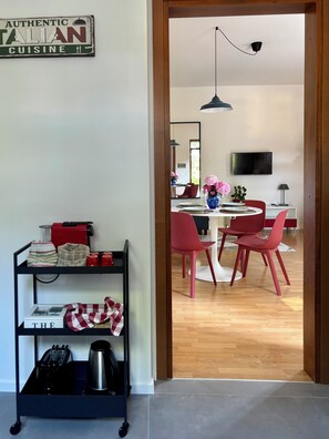 A modern kitchen with a black metal cart, red chairs, and a dining table. - New Listing (Corte Franca)