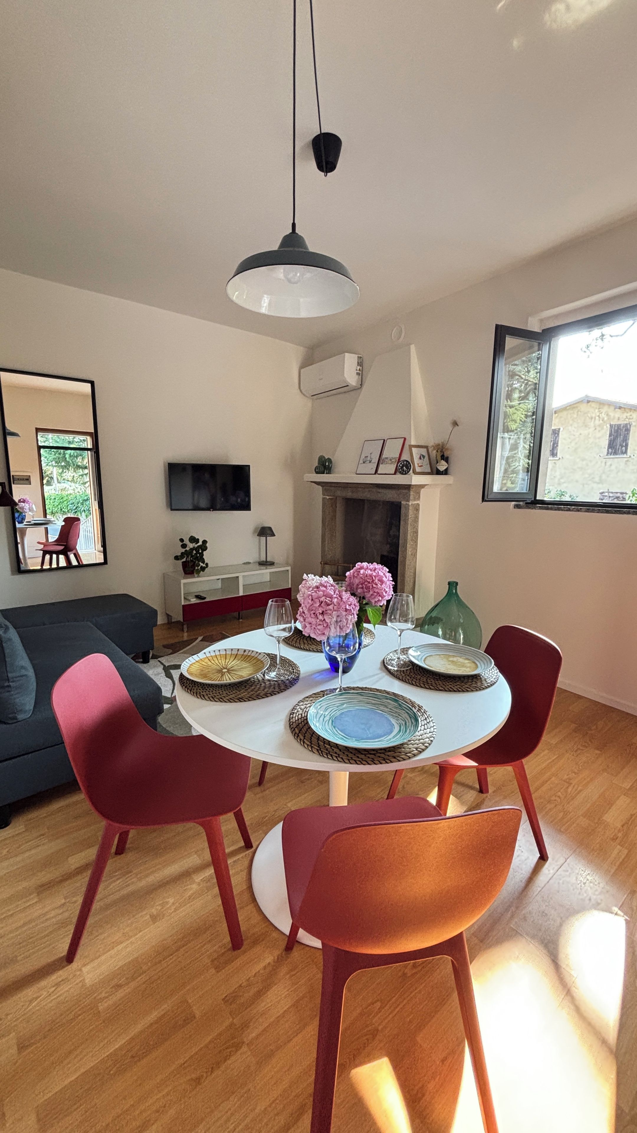 A dining area with a round table, four chairs, and a vase with flowers.