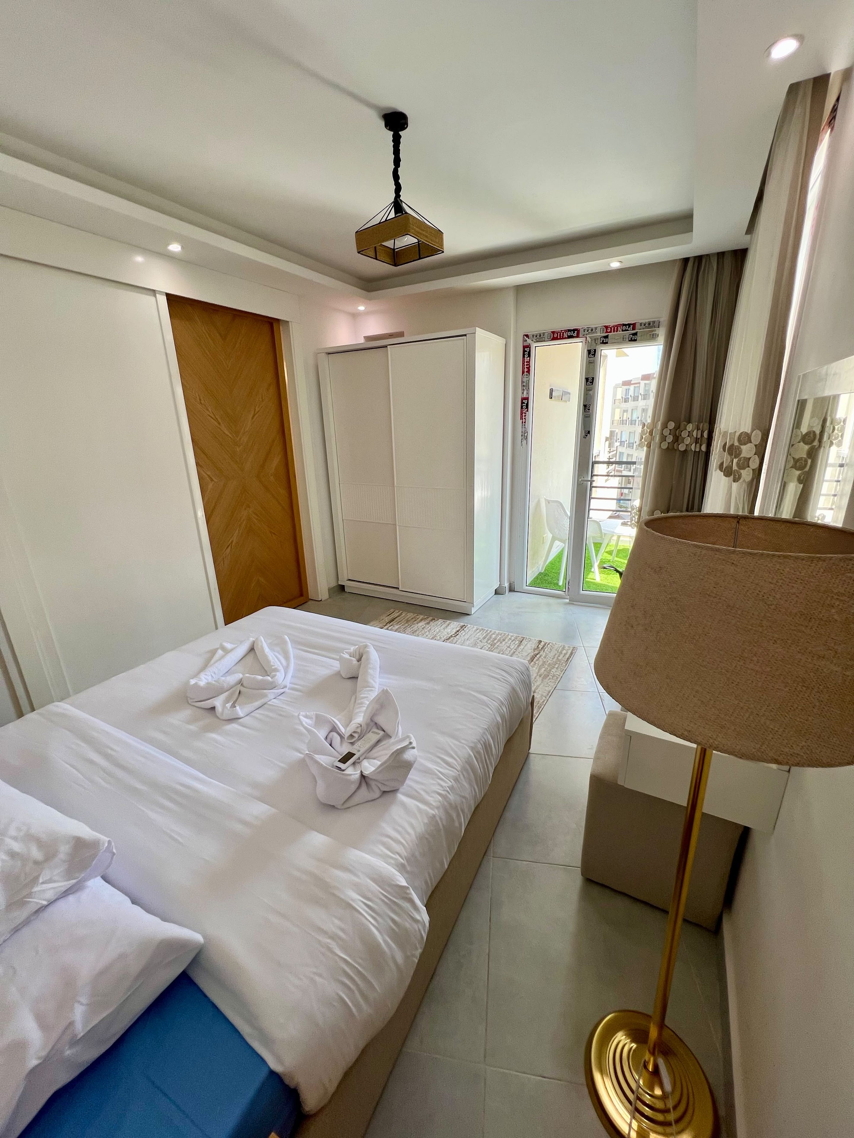 Ein Hotelzimmer mit Bett, Schreibtisch, Lampe und Blick ins Freie.