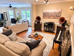 Un salón con sofá, mesa de centro, piano y objetos decorativos.