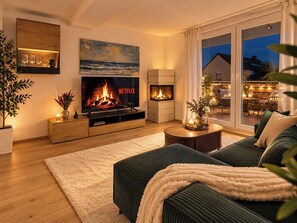 Ein modernes Wohnzimmer mit Kamin, Flachbildfernseher und Blick ins Freie.