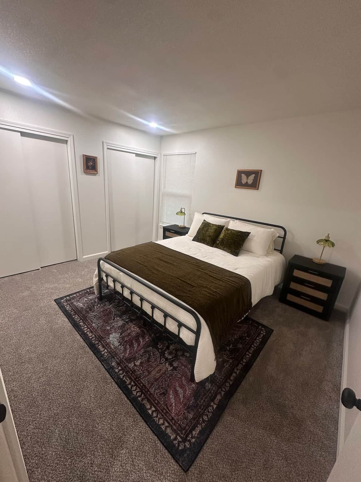 A bedroom with a bed, bedside tables, a rug, and a picture on the wall.