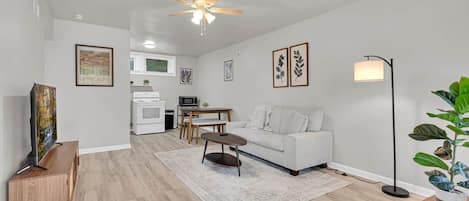 A modern living room with a sofa, coffee table, and a TV on a wooden cabinet.