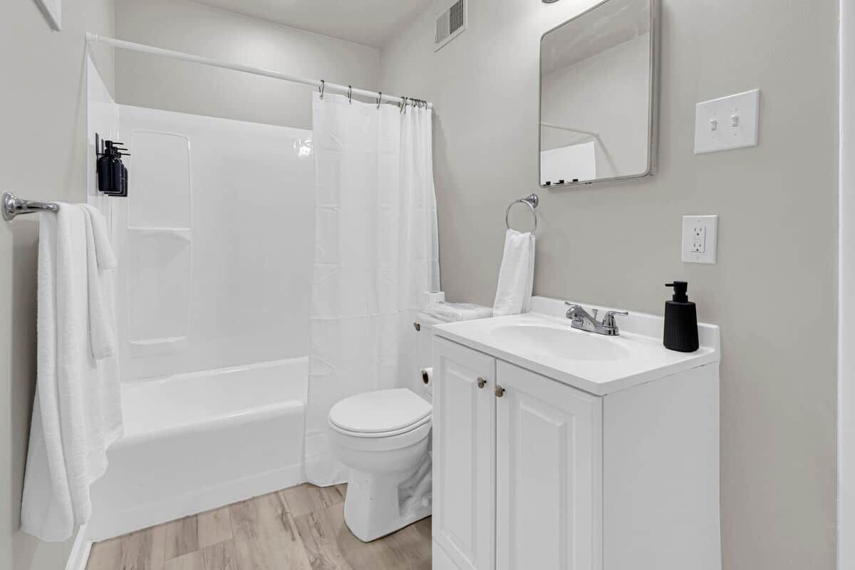 A bathroom with a bathtub, toilet, and a sink with a mirror above.