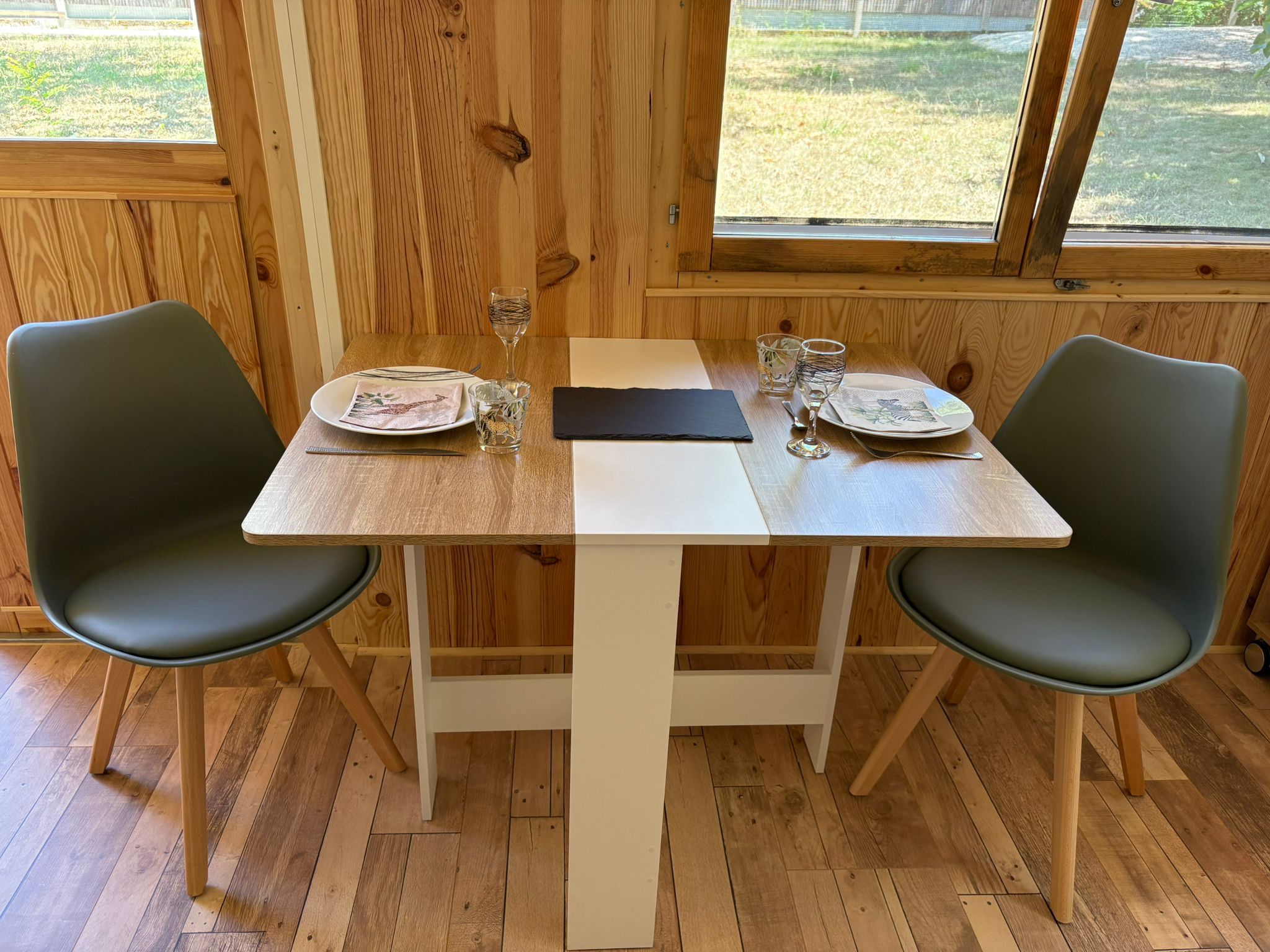 Een houten eettafel met twee stoelen, een witte tafelkleed en een zwarte servet.