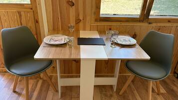 Een houten eettafel met twee stoelen, een witte tafelkleed en een zwarte servet.