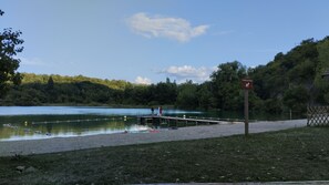 A lakeside scene with a wooden dock extending into the water, surrounded by lush greenery and a clear sky. - New Listing (Contrevoz)