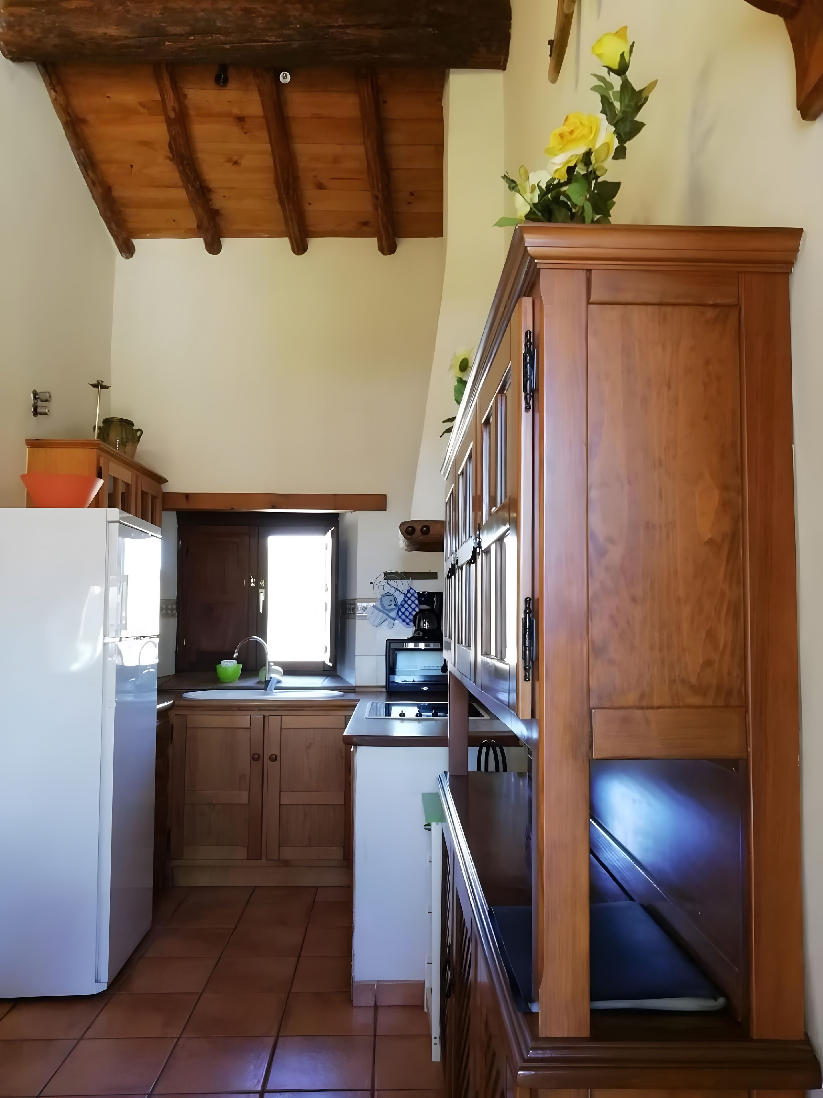 A kitchen with wooden cabinets, a white refrigerator, and a window providing natural light.
