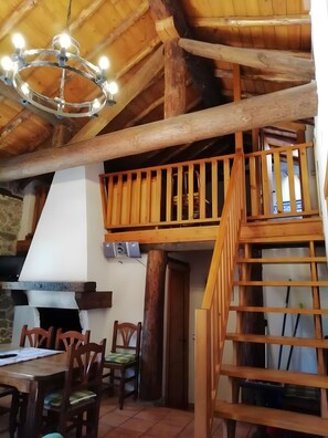 A rustic interior with a wooden staircase, a dining area with chairs, and a chandelier. - Country House 'Casa Rural La Pontezuela Abajo' with Shared Garden (Navarredonda de Gredos)
