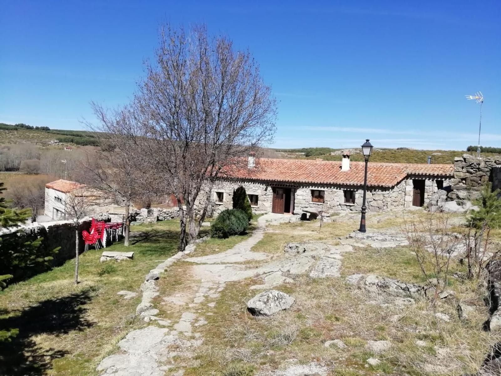A stone building with a tiled roof, a pathway leading to it, and a clear sky.