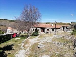 A stone building with a tiled roof, a pathway leading to it, and a clear sky. - Country House 'Casa Rural La Pontezuela Abajo' with Shared Garden (Navarredonda de Gredos)