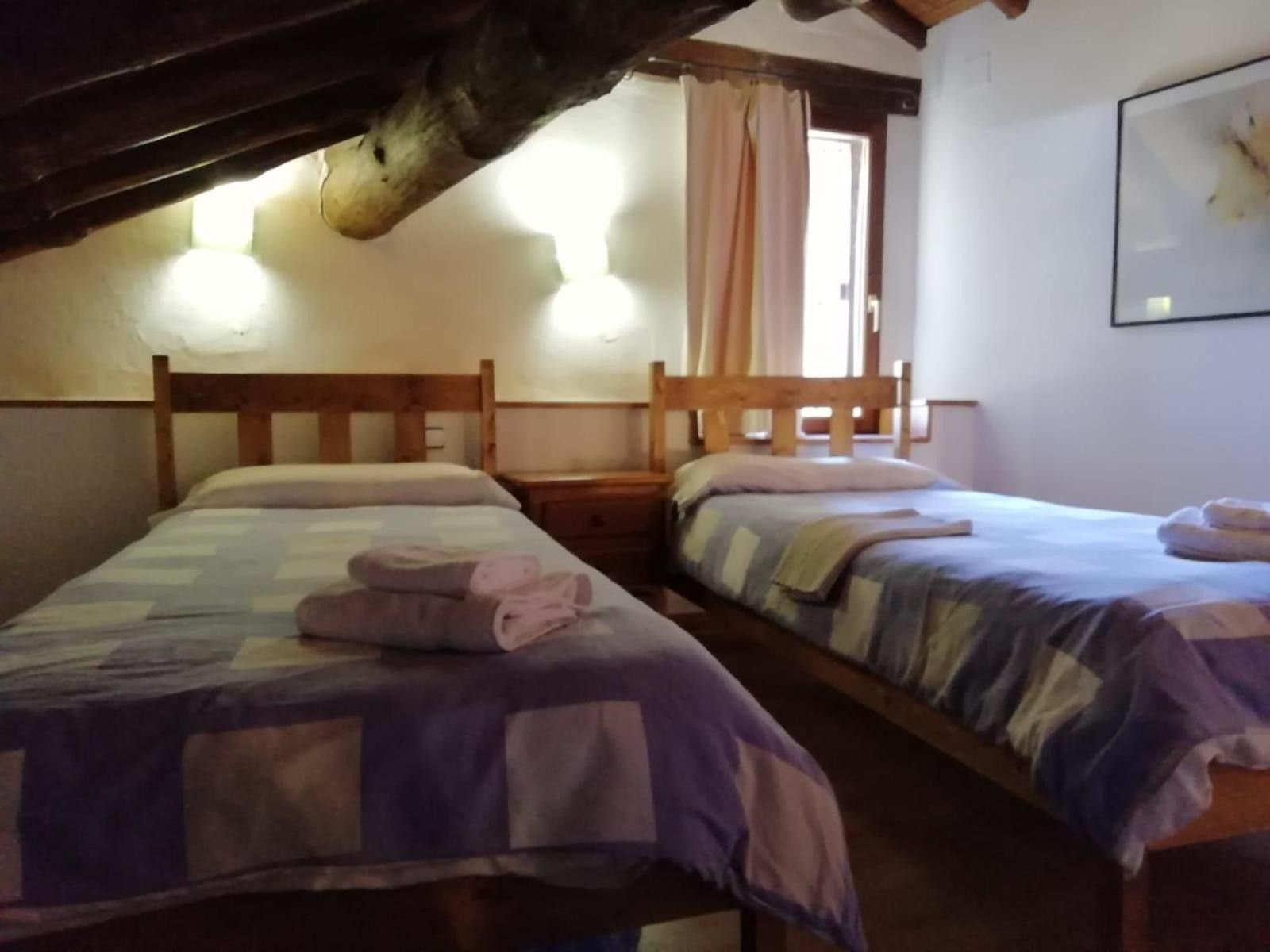 A room with two wooden beds, each with a headboard and a bedside table.
