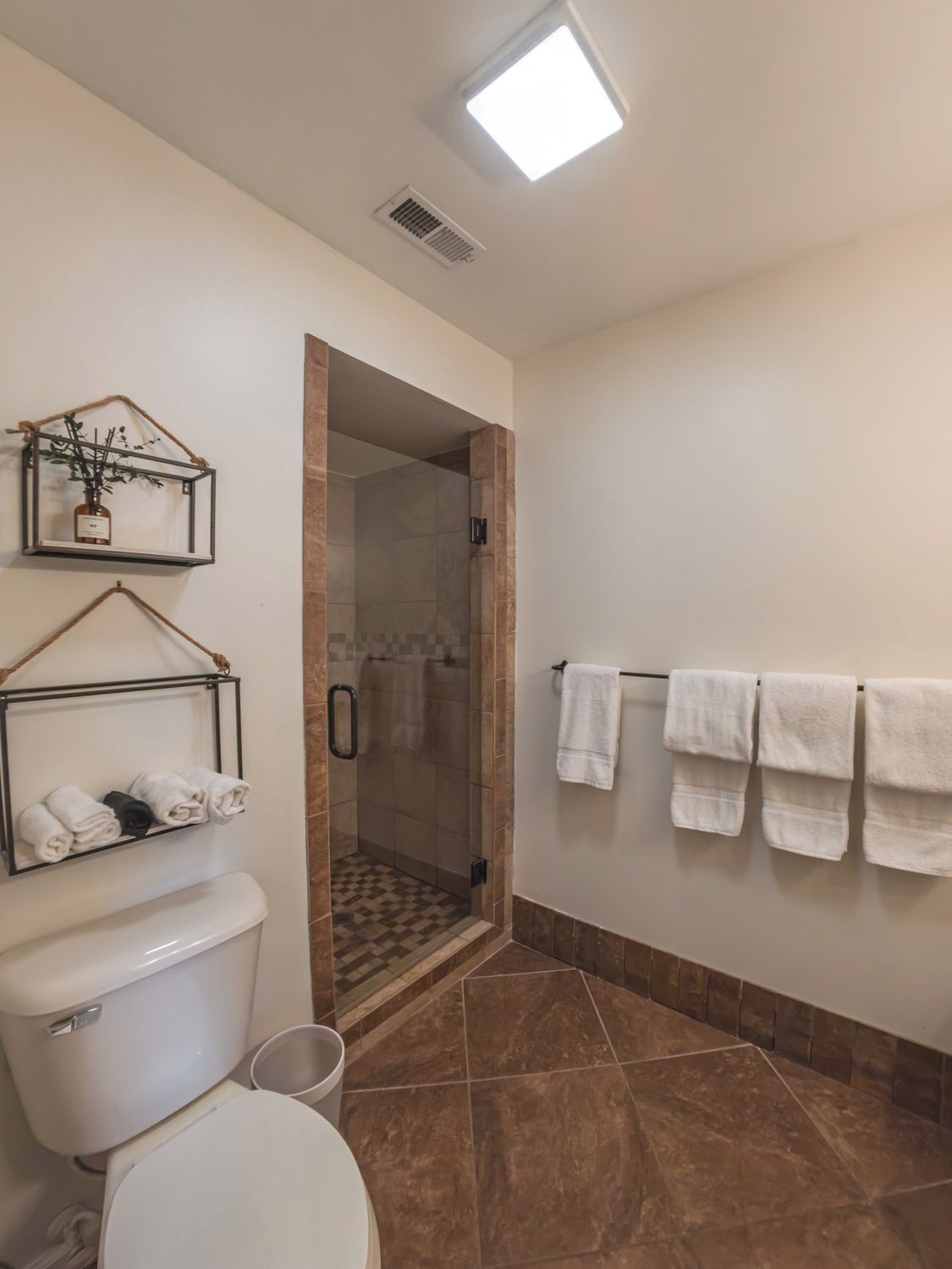 A bathroom with a toilet, a shower, and a towel rack.
