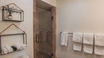 A bathroom with a toilet, a shower, and a towel rack.