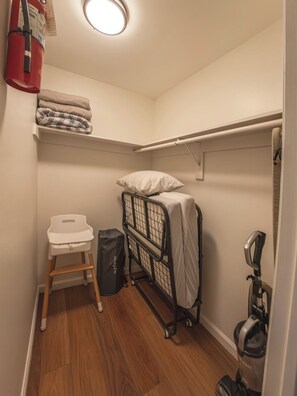 Een kleine kamer met een stapelbed, een klein stoeltje, een stofzuiger en een brandblusser.
