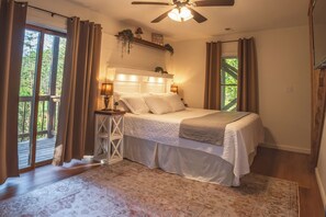 Une chambre à coucher avec un lit, des lampes de chevet, un ventilateur de plafond et une vue par la fenêtre.