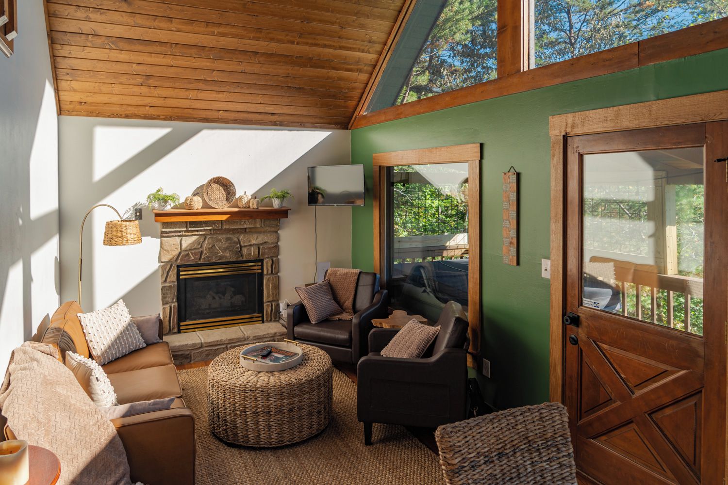 A cozy living room with a fireplace, comfortable seating, and a view through a glass door.