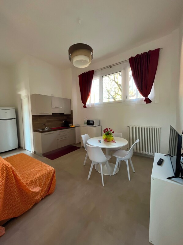 Een knus woongedeelte met een kitchenette, eethoek en een bed.