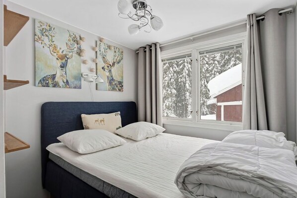Une chambre à coucher avec un lit, une tête de lit, une fenêtre avec des rideaux et des œuvres d’art murales.