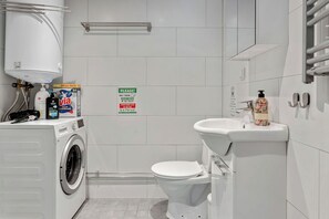 Une salle de bain moderne équipée d’un lave-linge, de toilettes et d’un lavabo.