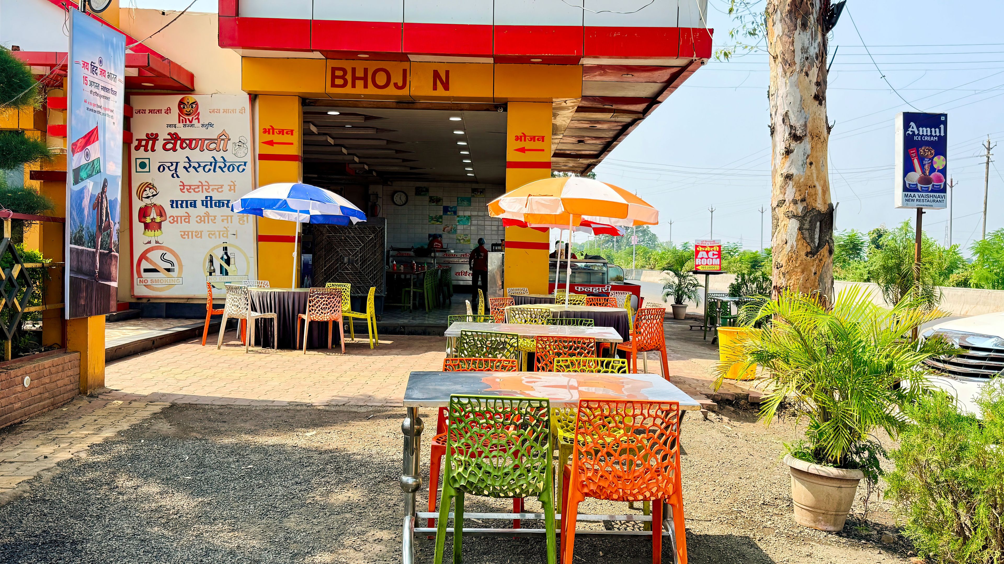 Un restaurante con mesas al aire libre, un letrero y un cartel de no fumar.