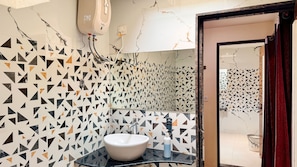 A bathroom with a geometric patterned wall, a white sink, and a mirror. - Maa Vaishnavi New Restaurant & Hotel (Omkareshwar)