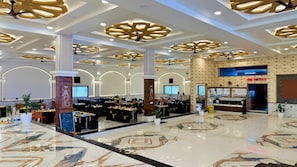 A spacious hotel lobby with a marble floor, high ceilings with decorative lighting, and a central column. - Maa Vaishnavi New Restaurant & Hotel (Omkareshwar)