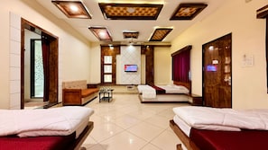 Habitación de hotel con dos camas, un sofá, un televisor y piso de baldosas.
